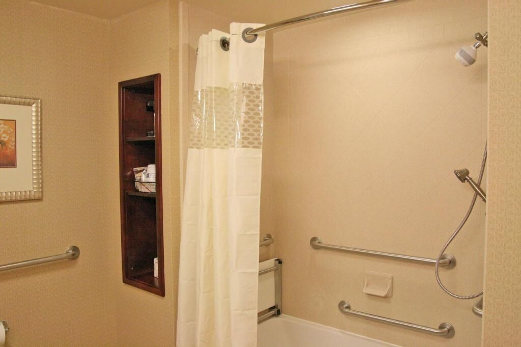 A bathroom with a shower, a toilet, and a shelf with toiletries.