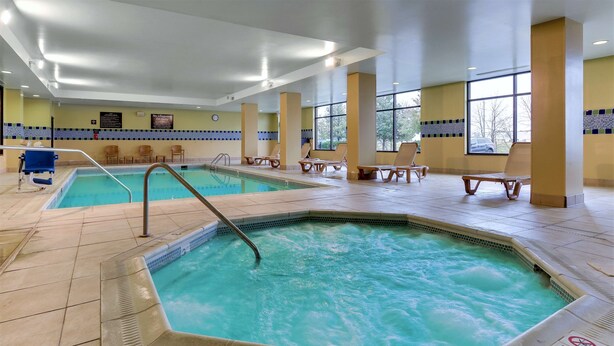 Ein Innenpool mit Whirlpool, Liegestühlen und Fliesenboden.