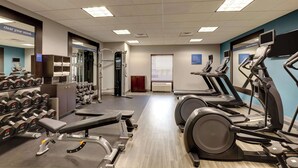 Ein Fitnessstudio mit Laufbändern, Kurzhanteln und Krafttrainingsgeräten.
