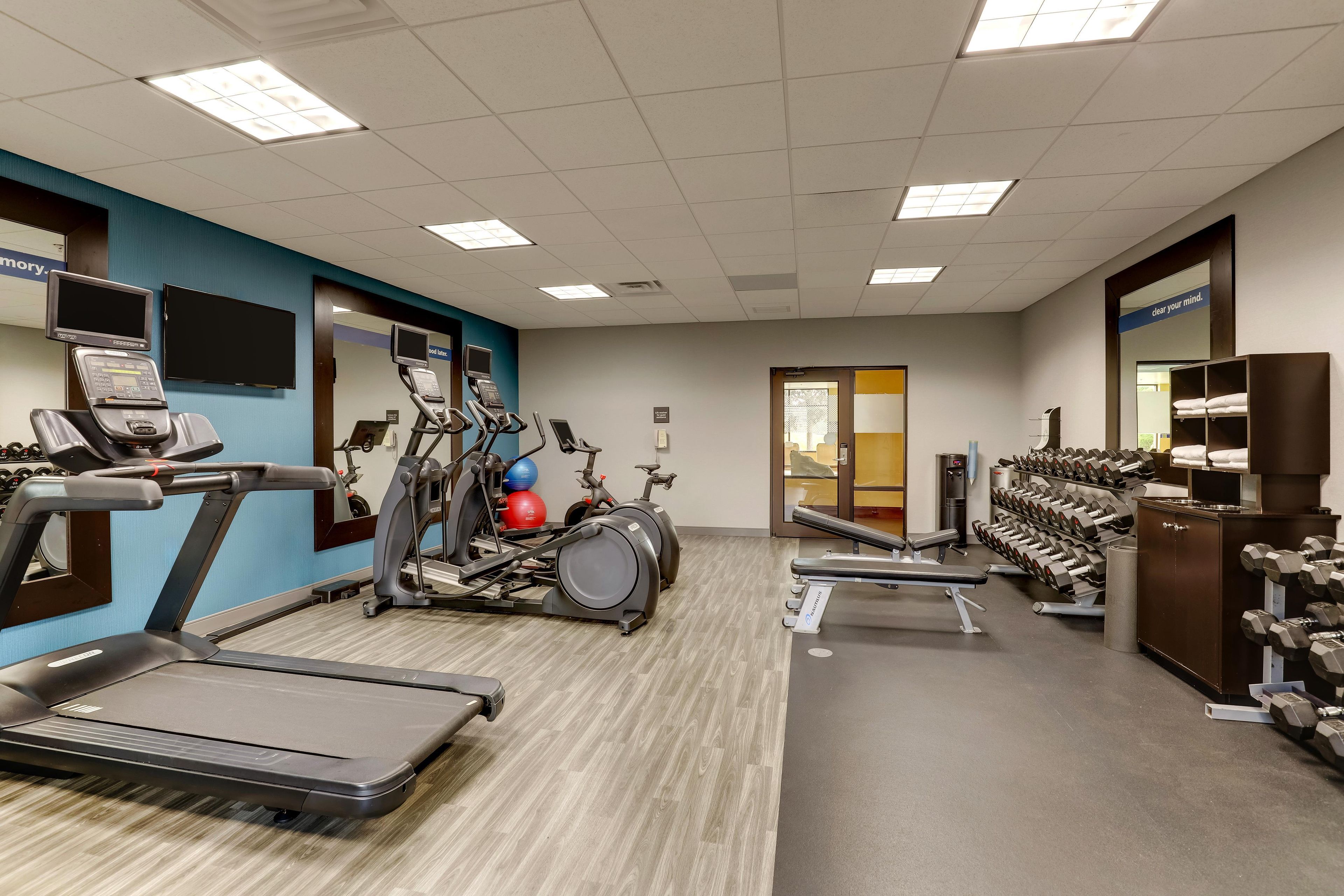A gym with treadmills, elliptical machines, and a weight bench.