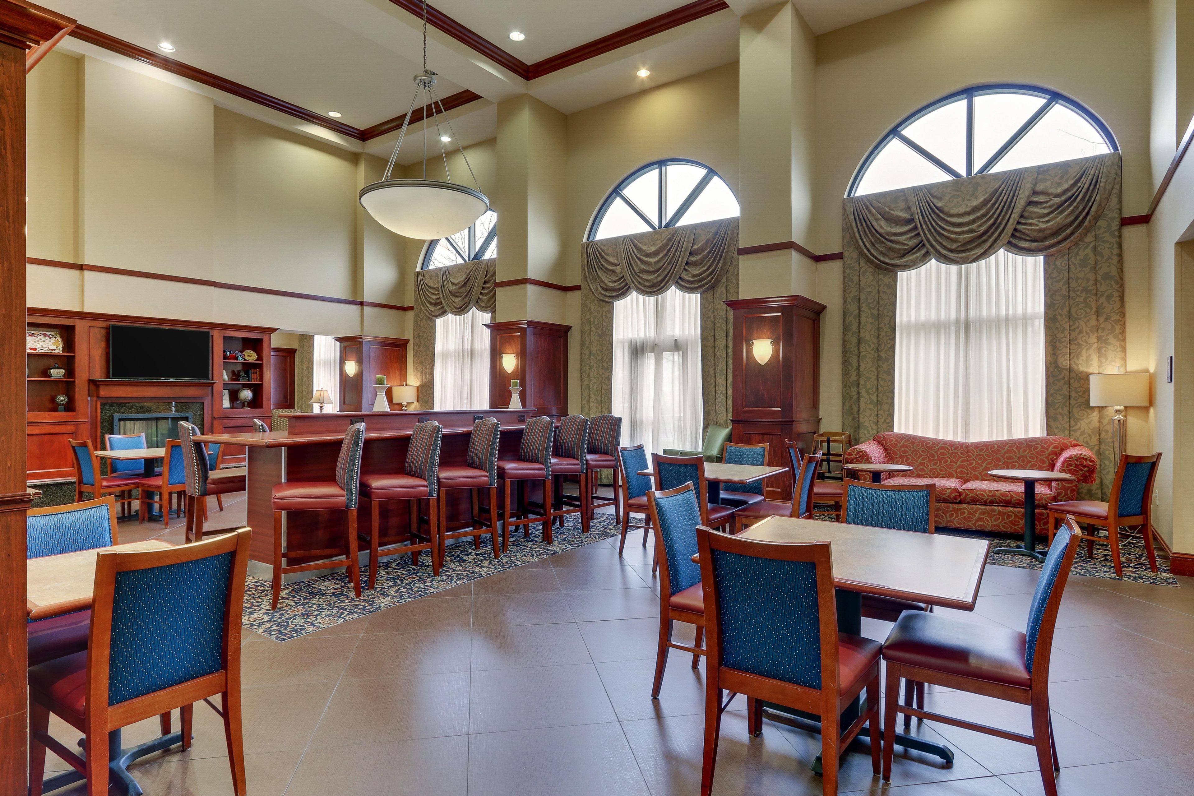 A hotel lobby with a bar area, seating, and large windows.