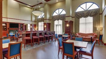 A hotel lobby with a bar area, seating, and large windows.