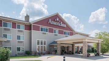 AmericInn's welcoming entrance features a covered area with columns and a beautifully manicured lawn.