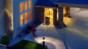 A house with a covered patio, stone pillars, and a red table. - AmericInn by Wyndham Newton (Newton)