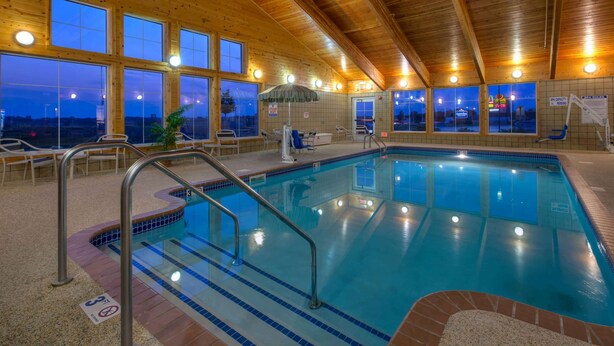 An indoor swimming pool with a wooden ceiling and large windows. - AmericInn by Wyndham Newton (Newton)