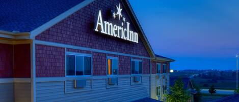 A two-story building with a sign reading "American Inn." It features a covered front porch with a stone facade and a clear view of the surrounding landscape.