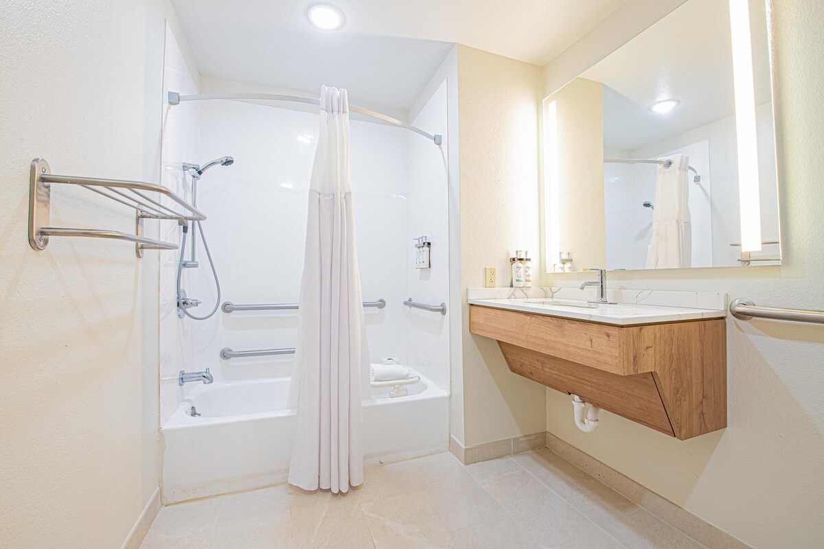 A modern bathroom with a walk-in shower, a wooden vanity with a sink, and a large mirror.