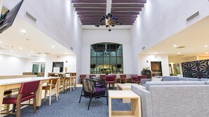A spacious indoor area with multiple seating options, including tables and chairs, and a large window providing natural light. - Staybridge Suites Lafayette by IHG (Lafayette)