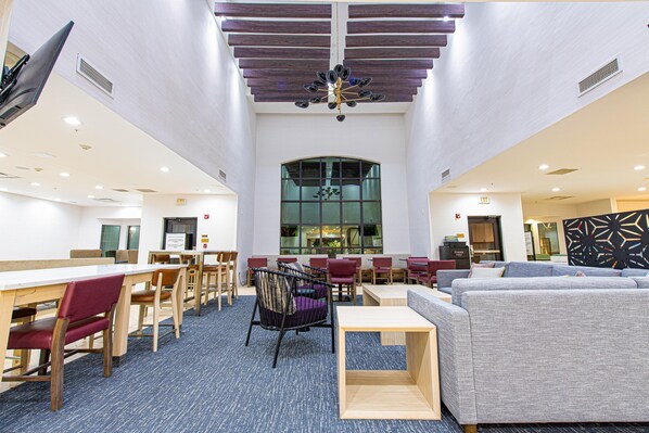A spacious indoor area with multiple seating options, including tables and chairs, and a large window providing natural light. - Staybridge Suites Lafayette by IHG (Lafayette)