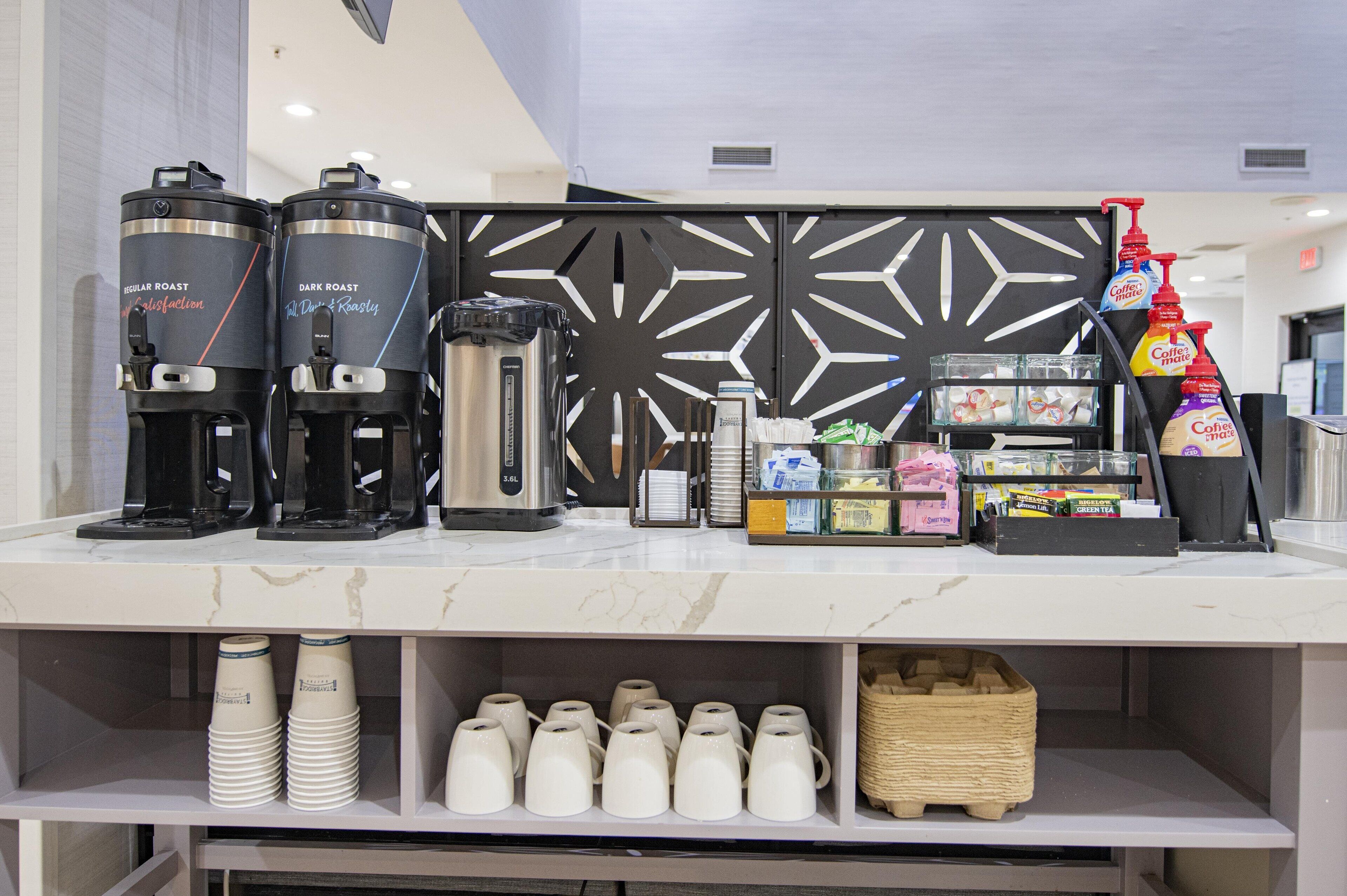 A coffee station with two coffee makers, a grinder, and various coffee products.