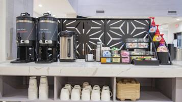 A coffee station with two coffee makers, a grinder, and various coffee products.