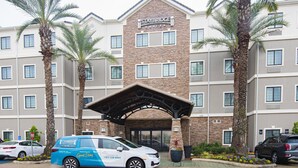 A Staybridge Suites hotel with a brick facade, multiple windows, and a covered entrance. - Staybridge Suites Lafayette by IHG (Lafayette)
