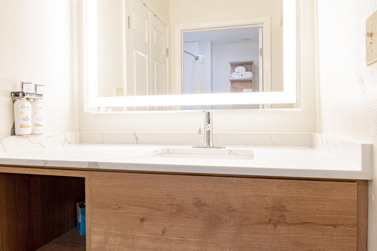 A bathroom with a white sink, a mirror, and a wooden cabinet below.