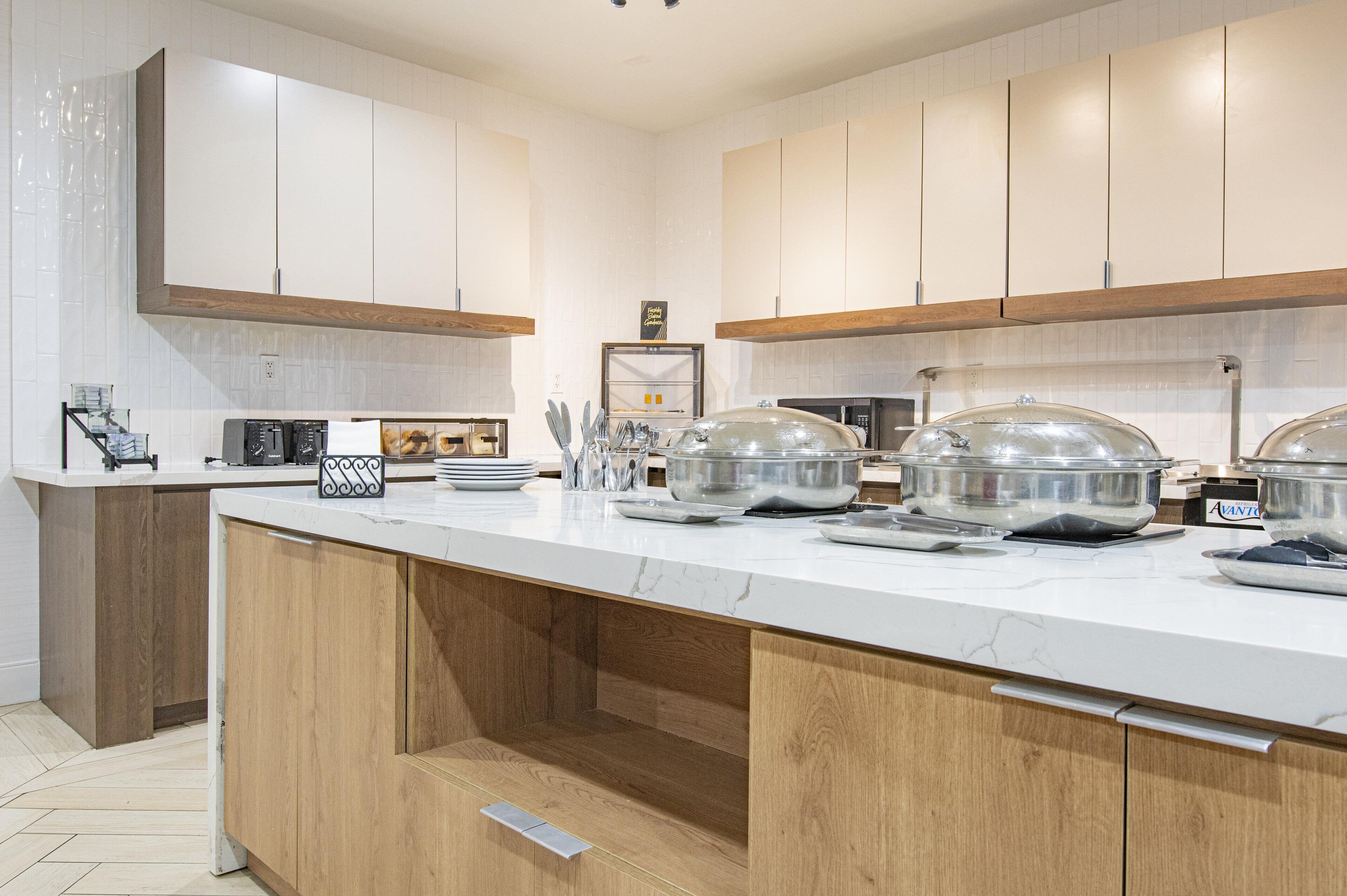 A modern kitchen with white cabinets, a marble countertop, and stainless steel appliances.