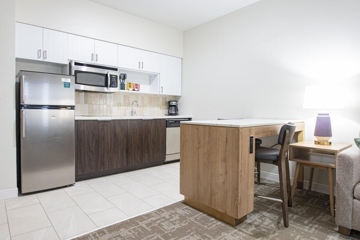 A modern kitchen with a built-in microwave, refrigerator, and coffee maker.