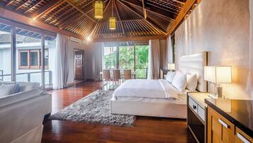 A modern hotel room with a large bed, a sitting area with a sofa, a dining table, and a view of the outdoors.