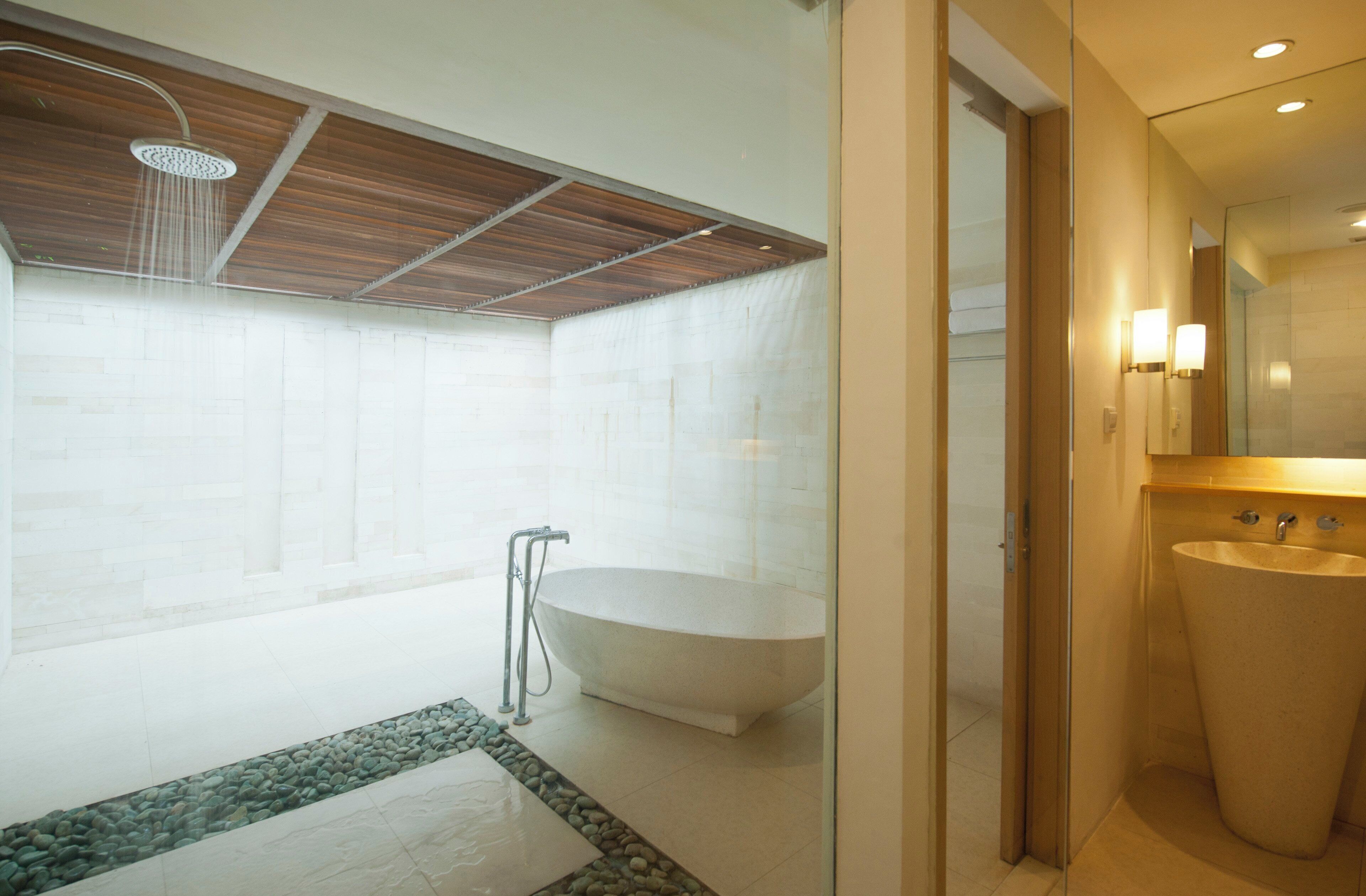 A modern bathroom with a freestanding bathtub, a showerhead, and a large sink.
