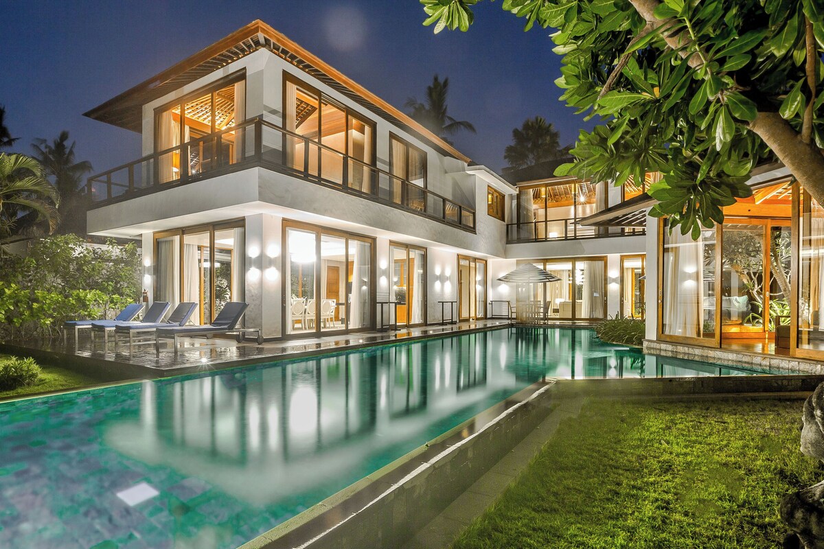 A modern two-story house with a swimming pool, large windows, and a well-maintained garden.