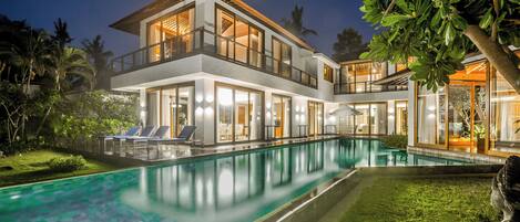 A modern two-story house with a swimming pool, large windows, and a well-maintained garden.