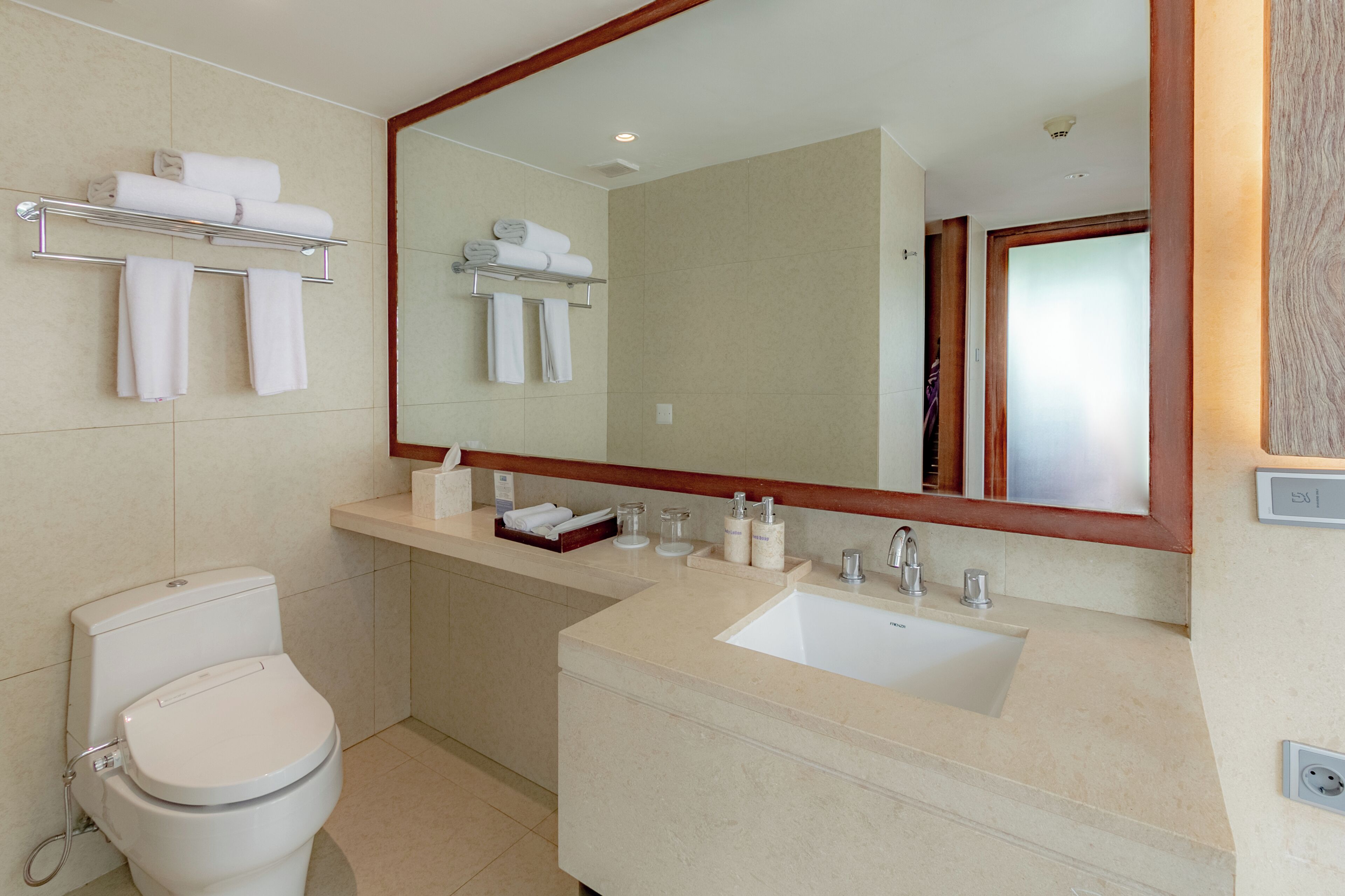 A modern bathroom with a toilet, sink, and a large mirror.
