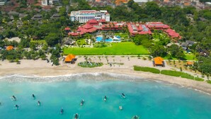 An aerial view of a resort with a beach, swimming pools, and a large building with a red roof. - Holiday Inn Resort Baruna Bali by IHG (Kuta)