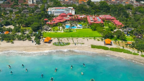An aerial view of a resort with a beach, swimming pools, and a large building with a red roof. - Holiday Inn Resort Baruna Bali by IHG (Kuta)