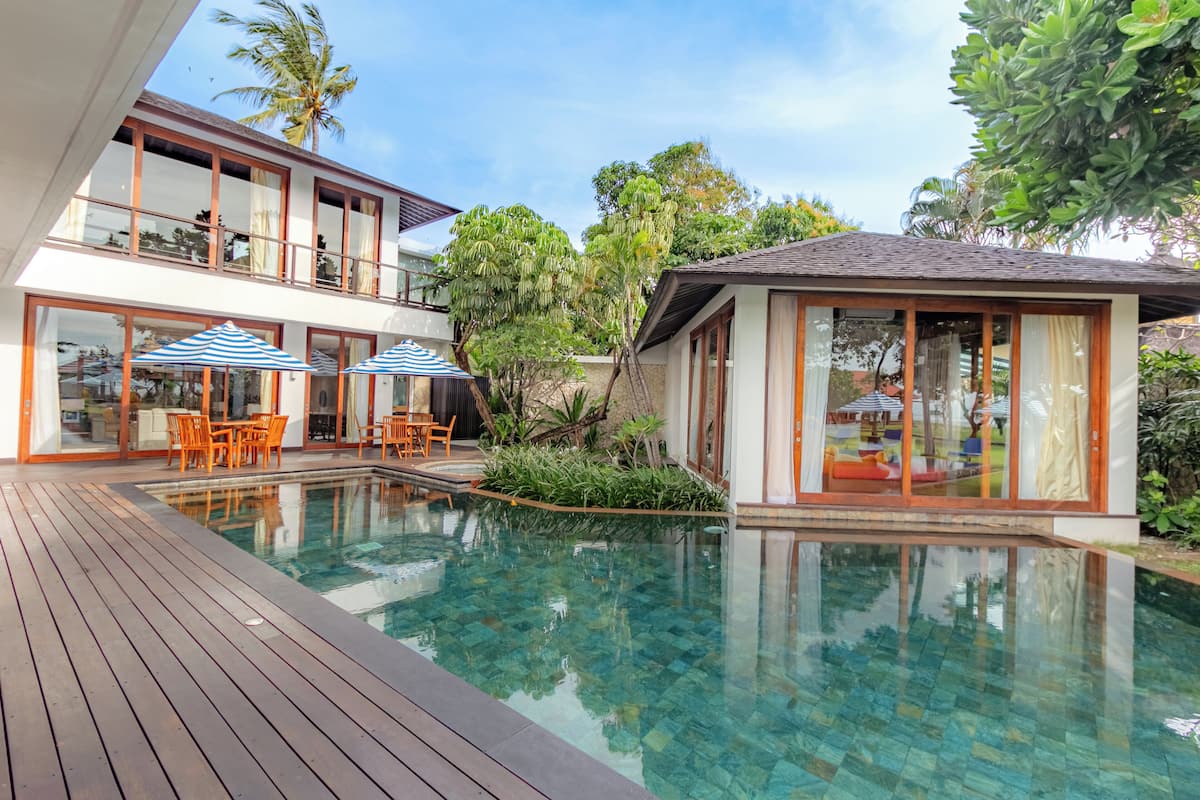 Une maison moderne dotée d’une piscine, d’une terrasse en bois et de mobilier d’extérieur.