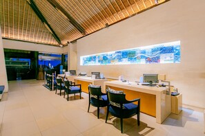 A reception area with a long counter, several chairs, and a large stained glass window. - Holiday Inn Resort Baruna Bali by IHG (Kuta)
