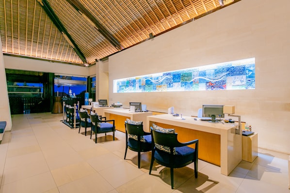 A reception area with a long counter, several chairs, and a large stained glass window. - Holiday Inn Resort Baruna Bali by IHG (Kuta)