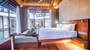 A modern hotel room with a wooden ceiling, large windows, a bed with white linens, and a seating area with a view of the pool. - Holiday Inn Resort Baruna Bali by IHG (Kuta)