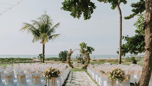 A beachside wedding venue with rows of white chairs, a floral aisle, and a view of the ocean. - Holiday Inn Resort Baruna Bali by IHG (Kuta)