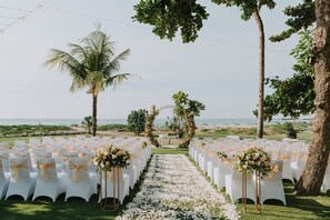 A beachside wedding venue with rows of white chairs, a floral aisle, and a view of the ocean. - Holiday Inn Resort Baruna Bali by IHG (Kuta)