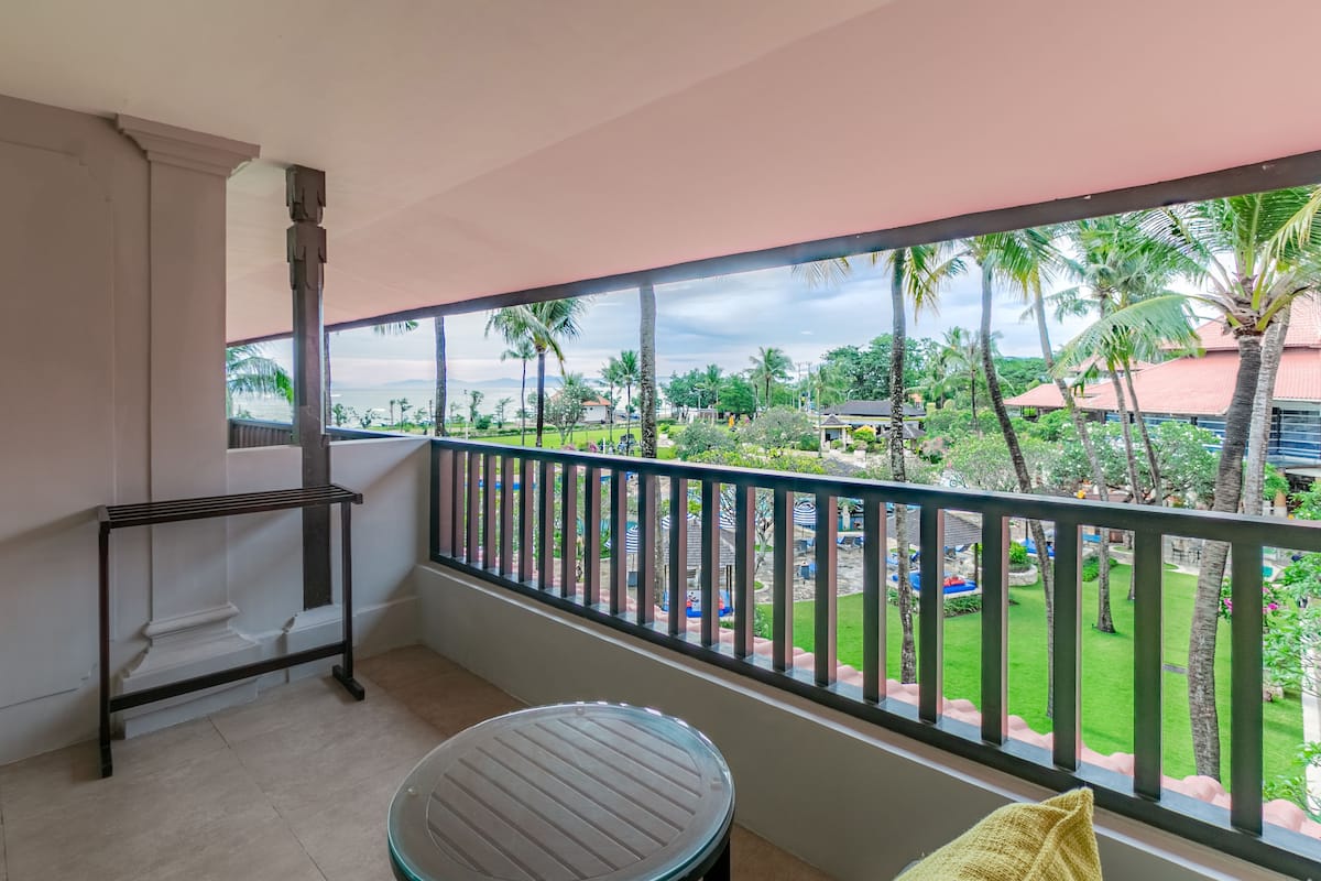 A balcony with a view of a landscaped garden and palm trees.