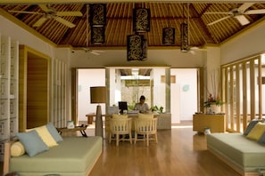 A spacious living area with a wooden ceiling, a dining table with chairs, and a sofa with cushions. - Holiday Inn Resort Baruna Bali by IHG (Kuta)