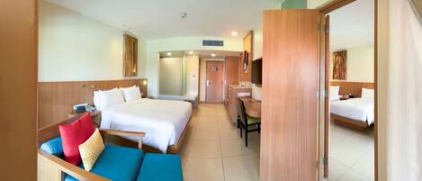 A hotel room with a bed, a desk, a chair, a sofa, and a bathroom.