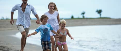 A family walking on a beach with a clear sky and calm sea.