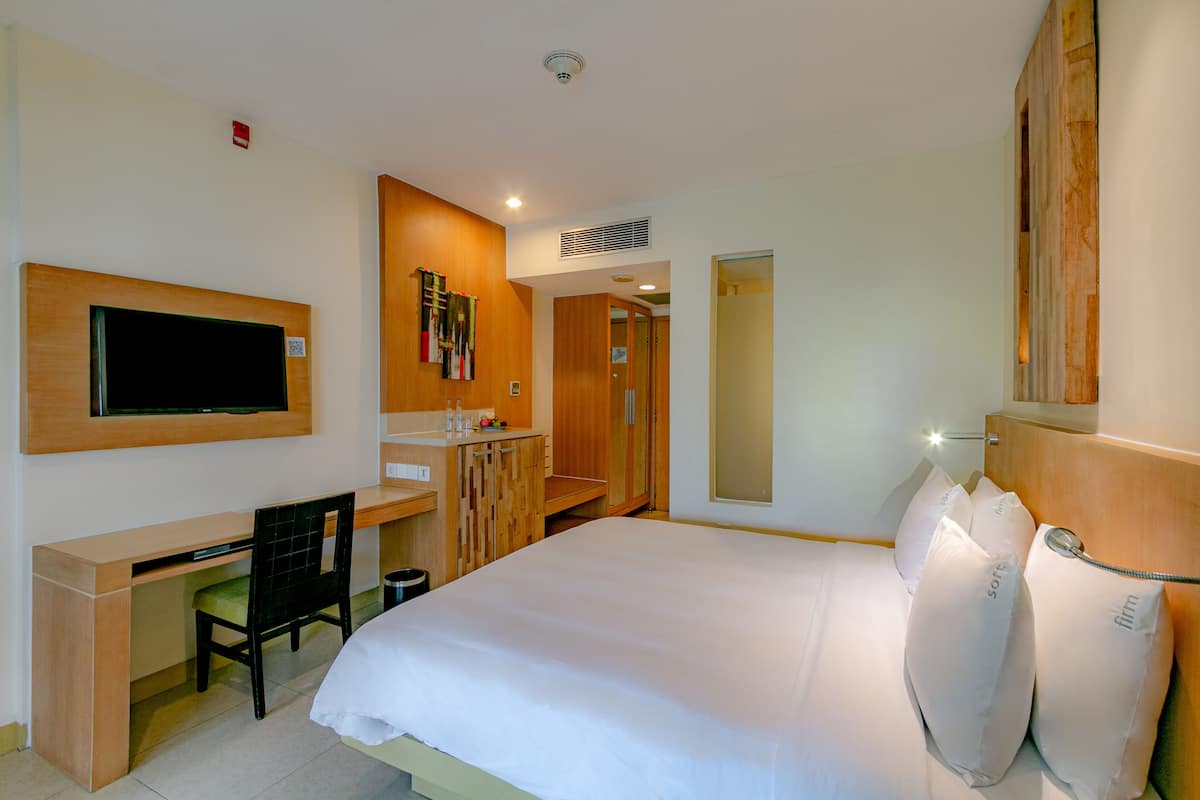 Une chambre d’hôtel équipée d’un lit, d’un bureau, d’une chaise, d’une télévision, d’un miroir et d’une armoire.