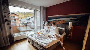 A bedroom with a large window, a bed, a nightstand, and a painting on the wall. - Break Sokos Hotel Levi (Kittila)