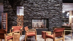A modern interior with a stone wall, wooden furniture, and a fireplace. - Break Sokos Hotel Levi (Kittila)