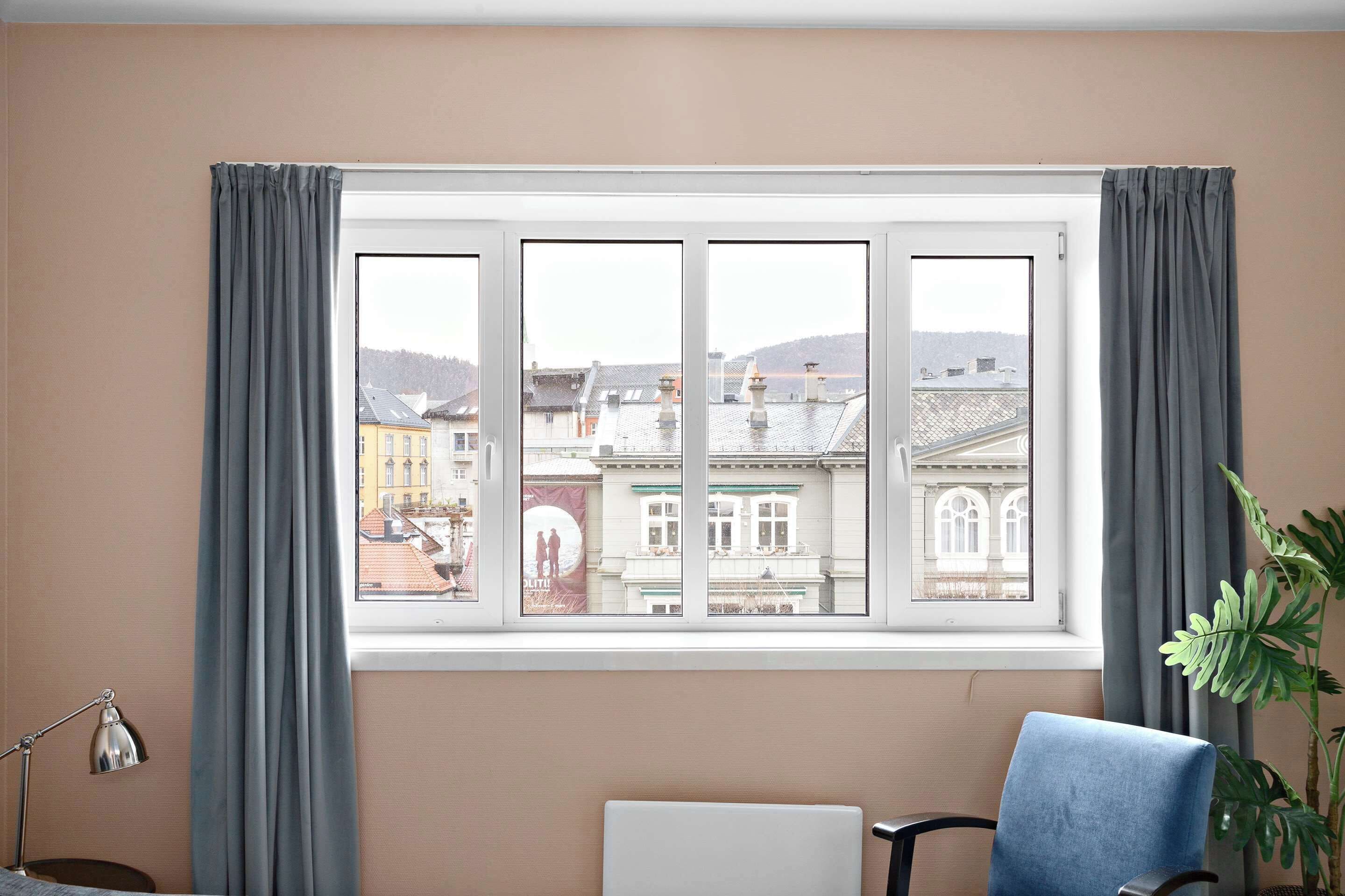 A room with a large window, a chair, a desk, and a lamp.