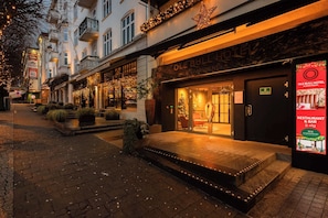 A hotel entrance with a sign for 'Ole Bull Hotel & Apartments,' a brick pathway, and outdoor seating. - Ole Bull, Best Western Signature Collection (Bergen)