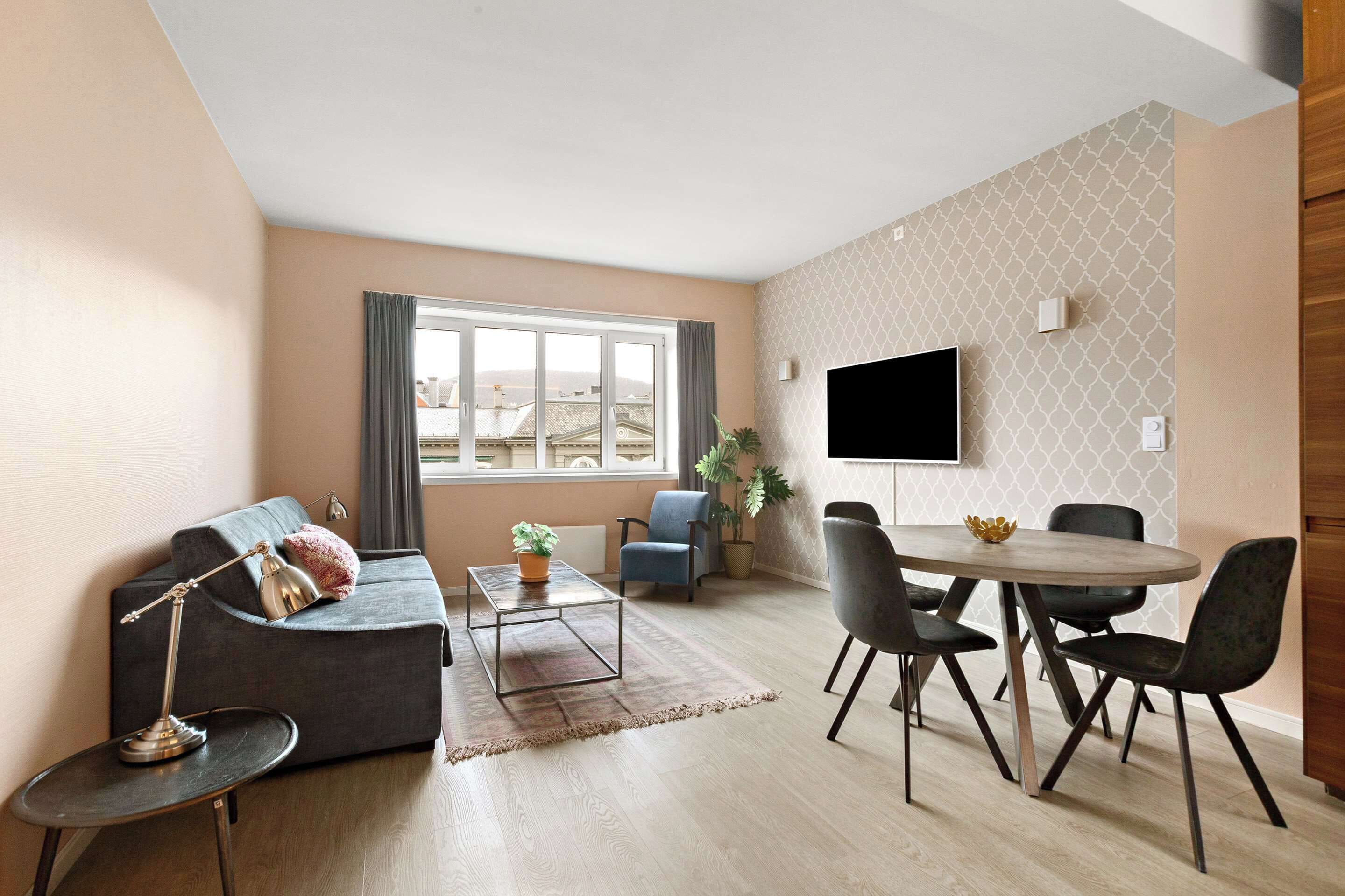 A modern living room with a sofa, coffee table, TV, and dining area.