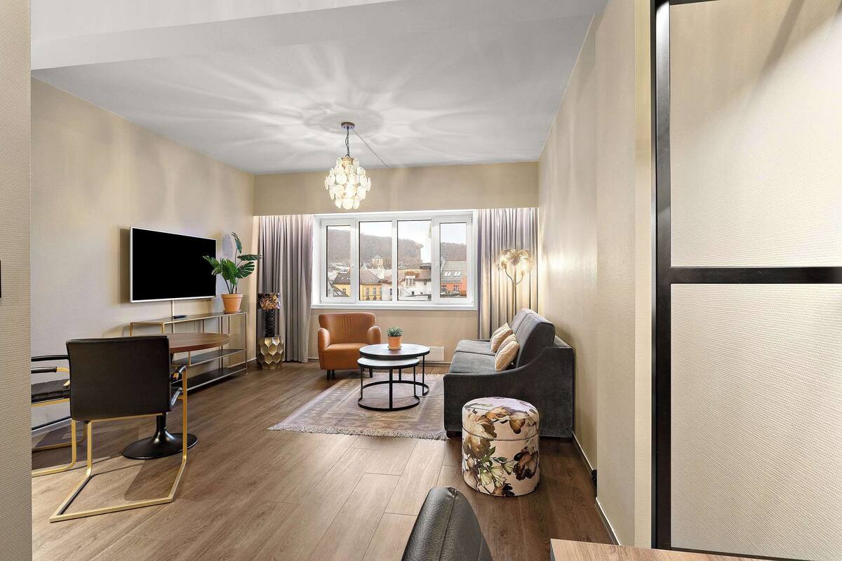 Una sala de estar moderna con una televisión de pantalla plana, un sofá, una mesa de centro y un comedor con una silla y una mesa.