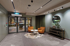A lobby with a round table, two armchairs, a console table with a mirror, and a door leading outside. - Ole Bull, Best Western Signature Collection (Bergen)