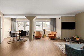 A modern living room with a dining area, a flat-screen TV, and a view of the outdoors.