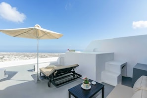 A rooftop terrace with a white lounge chair, a table with a potted plant, and a large umbrella. - Carpe Diem Santorini (Santorini)