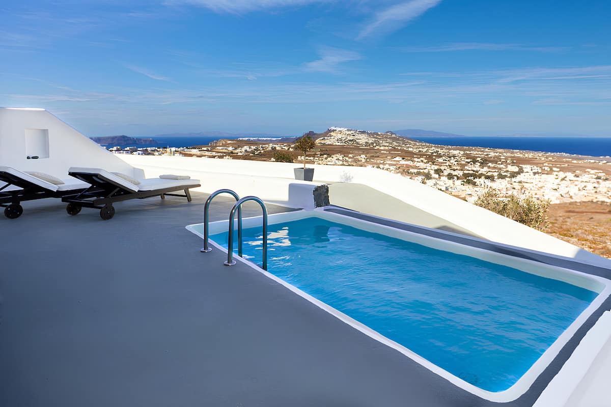 A rooftop pool with lounge chairs and a view of a coastal village.