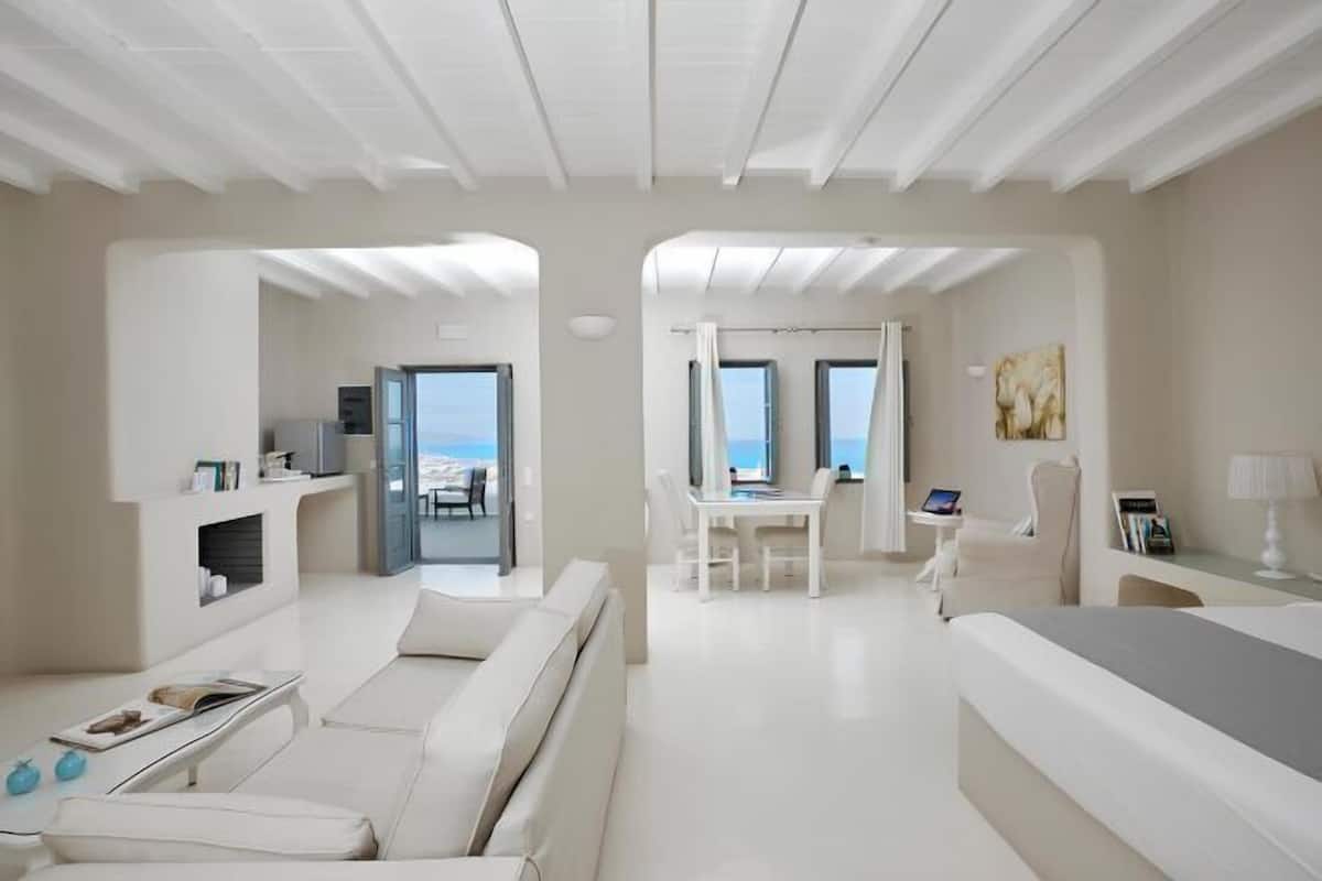 A modern hotel room with a balcony, a dining area, and a living space.