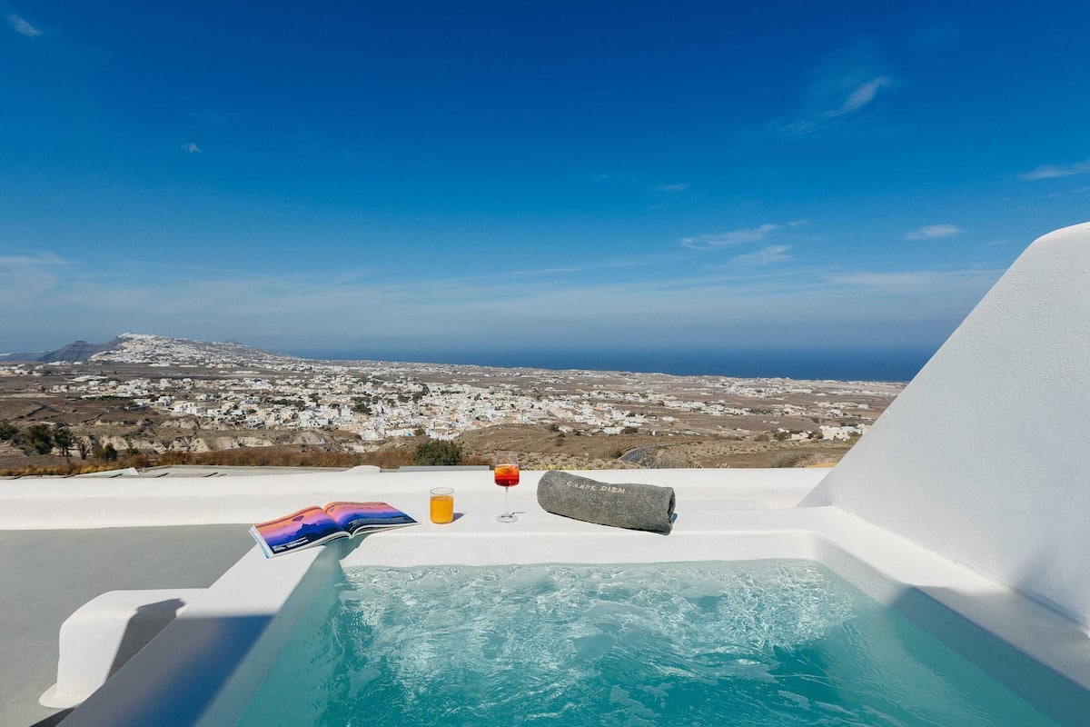 A pool area with a book, a glass of orange juice, and a bottle of water.