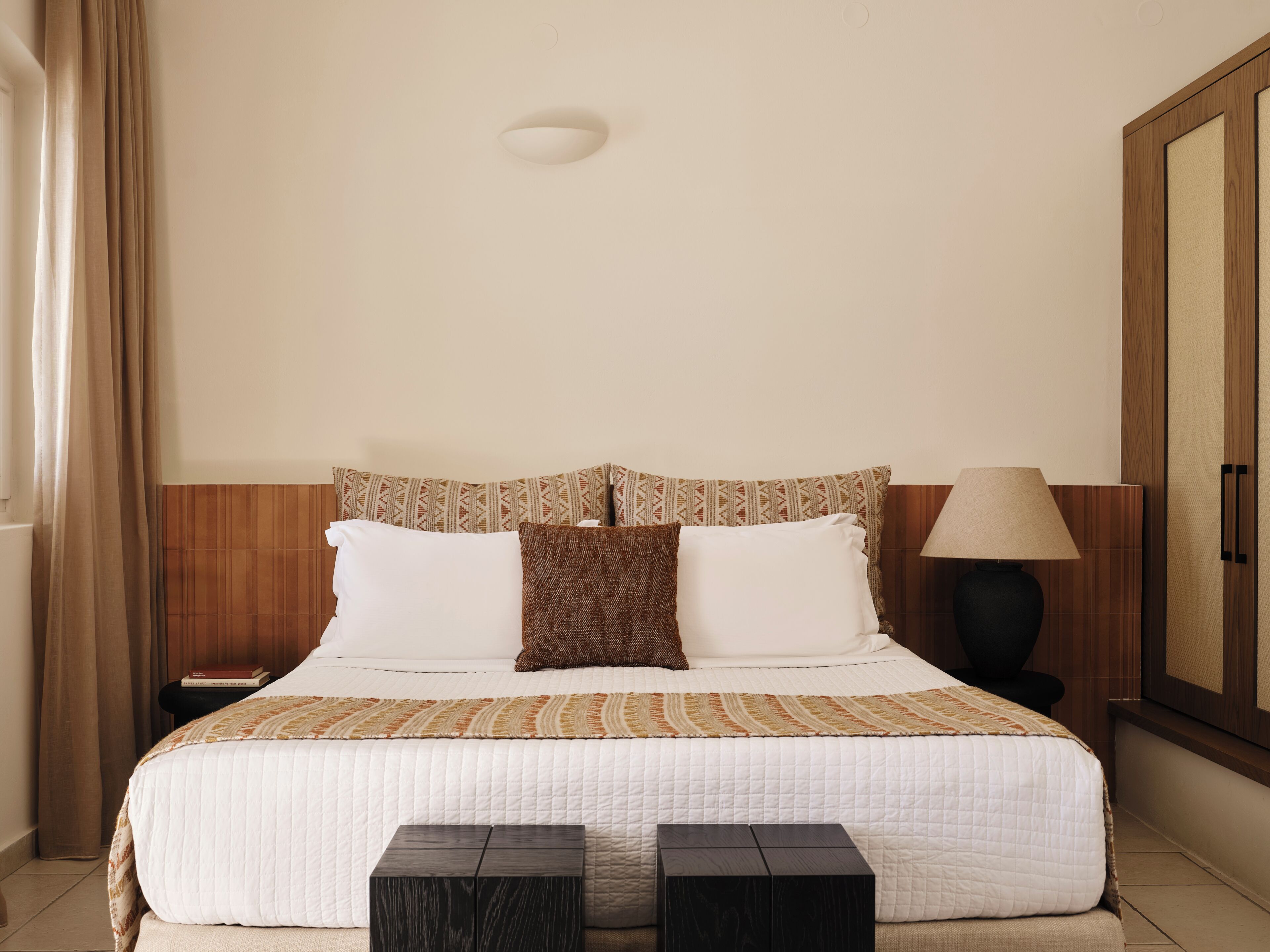 Une chambre d’hôtel avec un lit, une table de chevet, une lampe et une armoire.